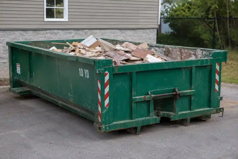 A green 10-yard roll-off dumpster with red and white diagonal safety stripes on the sides, partially filled with construction debris